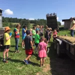 Fun learning is So much a part of Farm Camp. Here children wait to jump on the wagon for a tour of Backbone Food Farm in Pleasant Valley with All Earth Eco Tours.